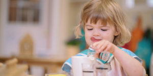 Child pouring liquid into measuring cup