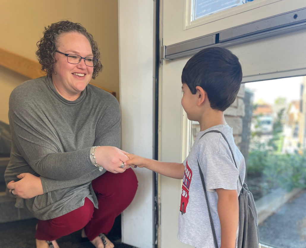 Young student shaking hands with a teacher at Nelephant Montessori School on his first day